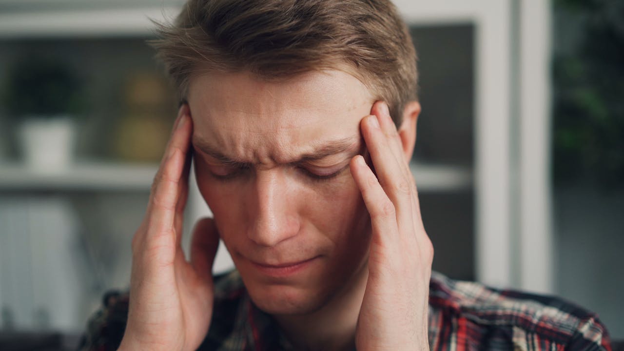 A man with a headache is holding his head